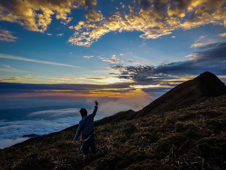 Climber standing on the narrow Knife Edge ridge of Mt. Halcon above a sea of clouds in Oriental Mindoro