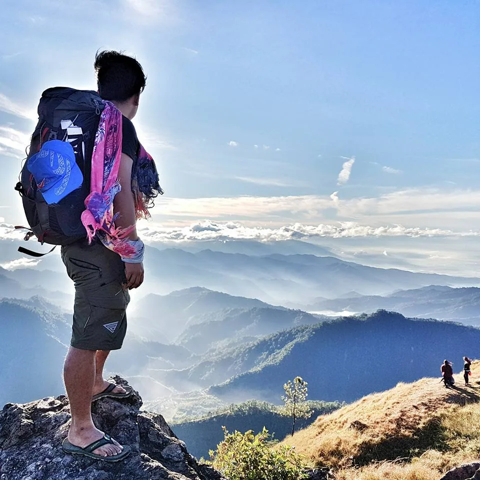 Hiker standing on Gungal Rock with Cordillera mountain ranges stretching to the horizon