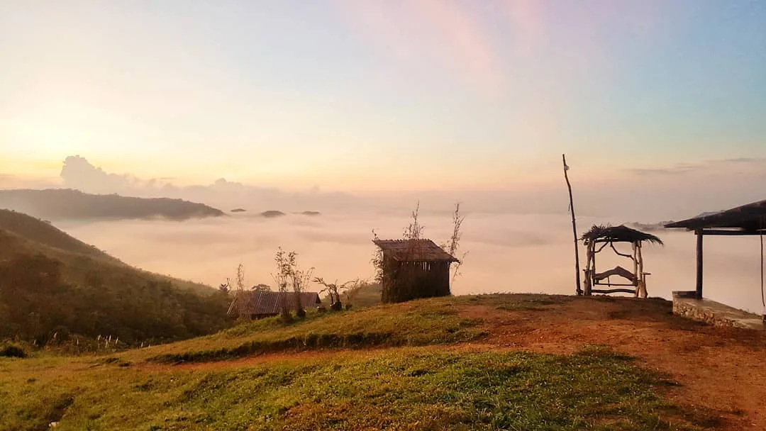 Hiker standing at Mt. Kulis summit with sea of clouds filling the valley below at sunrise