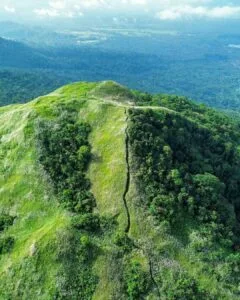 White summit cross on Mt. Kalisungan's open grassland peak with panoramic Laguna countryside views