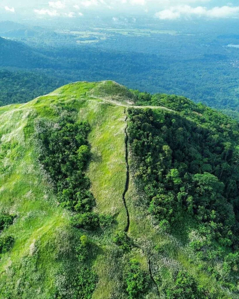 White summit cross on Mt. Kalisungan's open grassland peak with panoramic Laguna countryside views
