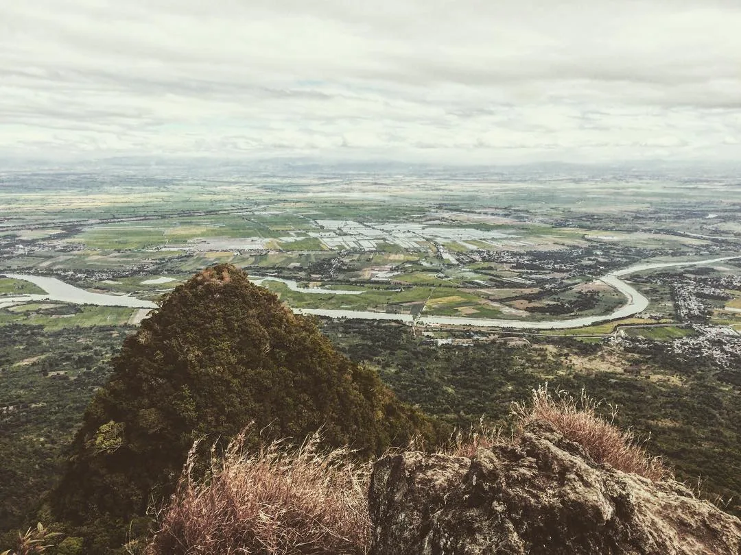 Hiker standing at the North Peak summit of Mt. Arayat in Pampanga, with sweeping 270-degree views of the Central Luzon plains below