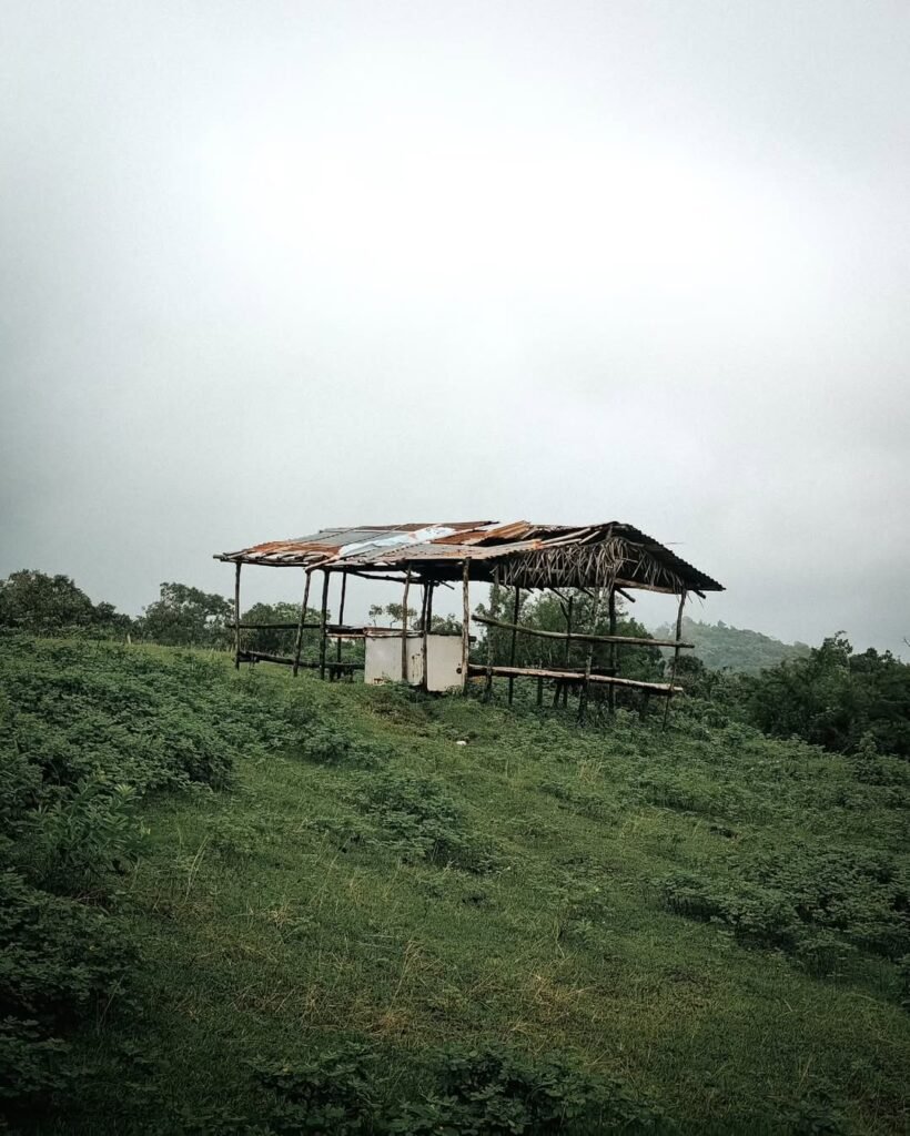 Small nipa hut rest stop at the summit of Mt. Lantik in Nasugbu, Batangas, with bamboo benches and views of nearby peaks
