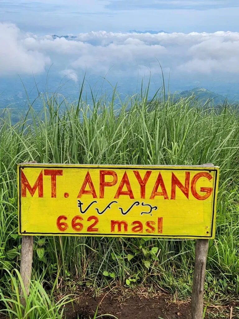 Hiker standing at the rocky summit of Mt. Apayang in Nasugbu, Batangas with panoramic views of the West Philippine Sea and surrounding mountains