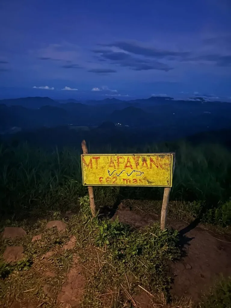 Hiker standing at the rocky summit of Mt. Apayang in Nasugbu, Batangas with panoramic views of the West Philippine Sea and surrounding mountains