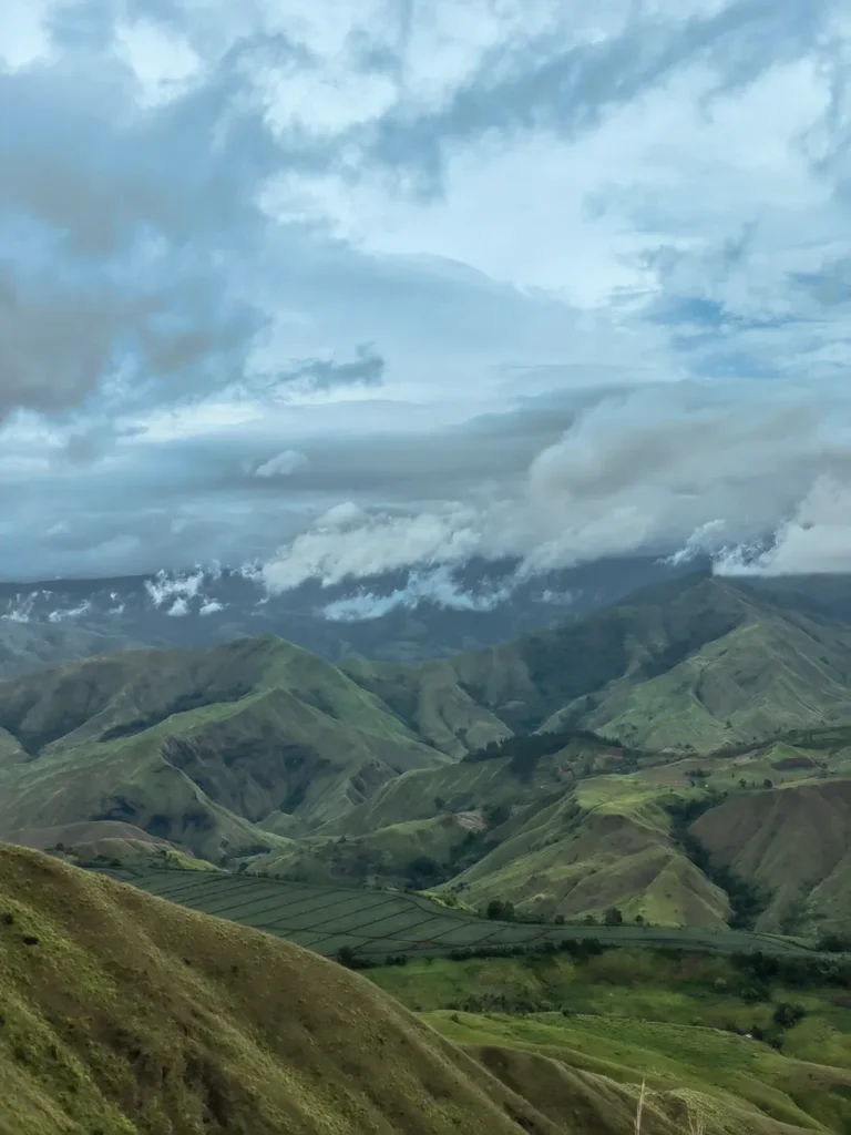 Wide view from Panimahawa Ridge showing patchwork farms below and low clouds forming over the valley in Impasug-ong, Bukidnon.