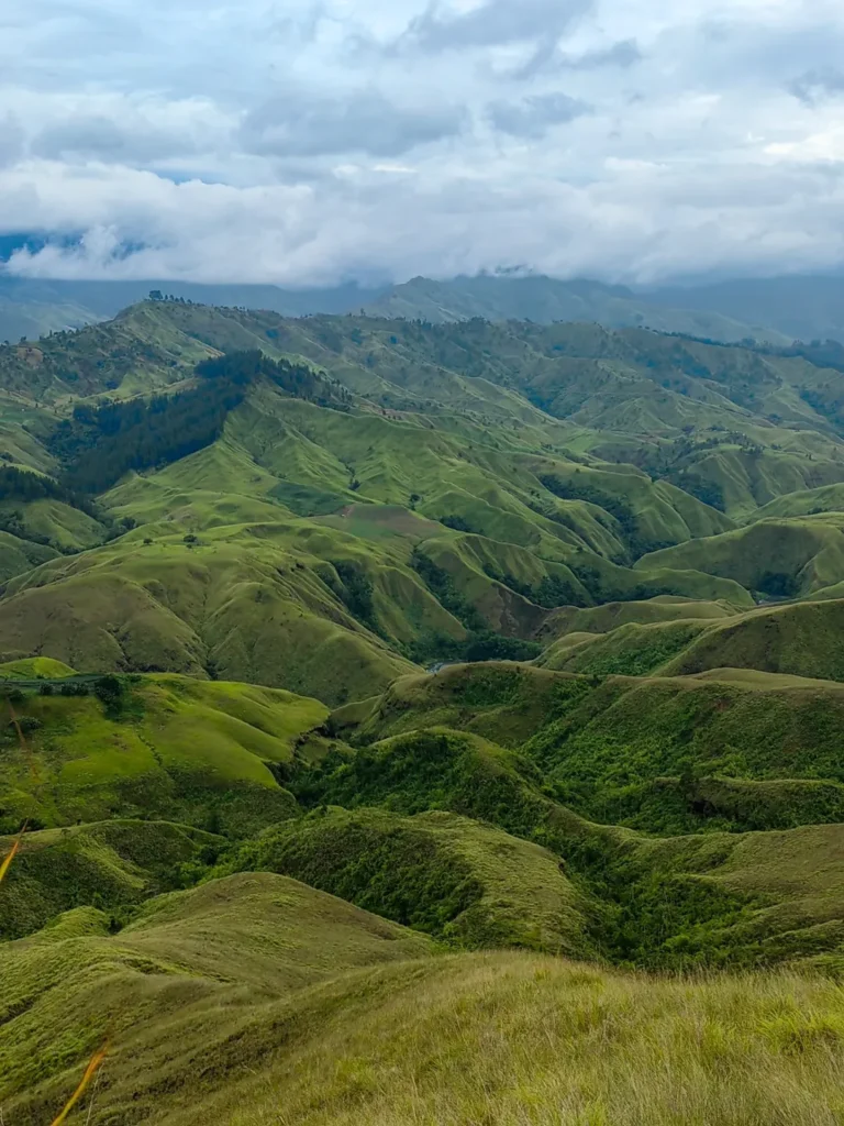 Panoramic ridgeline scene from Panimahawa Ridge, Impasug-ong—rolling grasslands, valleys, and thick clouds above the peaks.