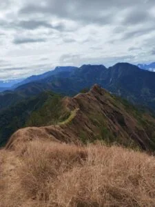 Hiker standing at the exposed summit ridge of Mt. Kimat Patil-Ao in Cervantes, Ilocos Sur, with sweeping Cordillera views