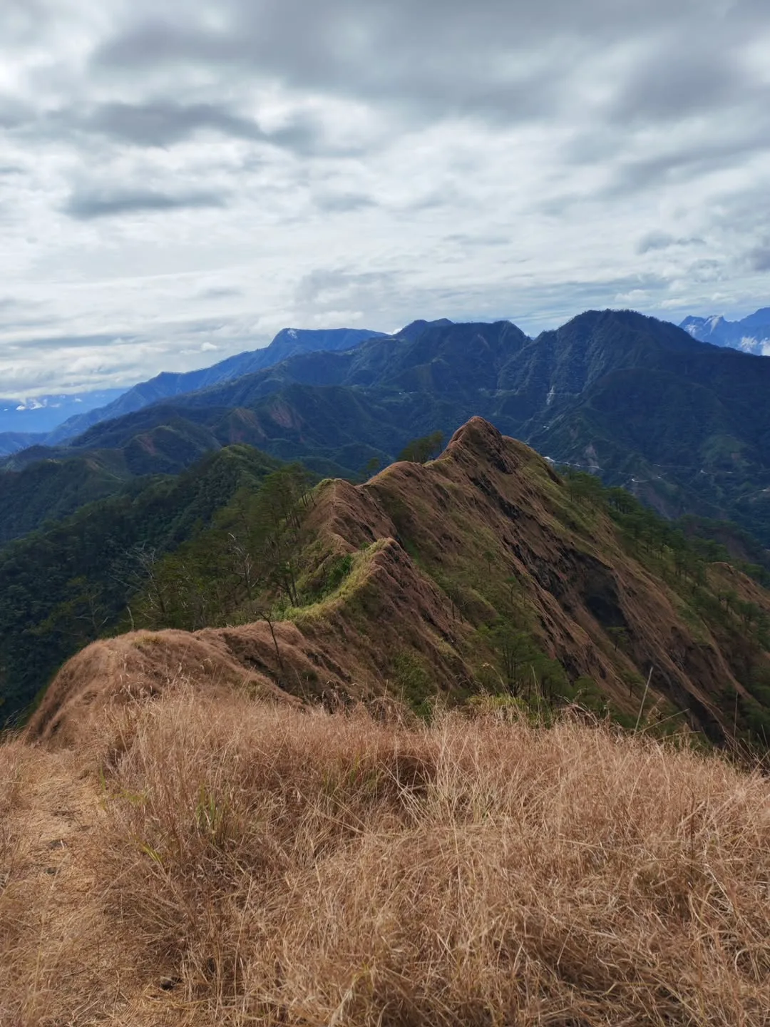 Hiker standing at the exposed summit ridge of Mt. Kimat Patil-Ao in Cervantes, Ilocos Sur, with sweeping Cordillera views