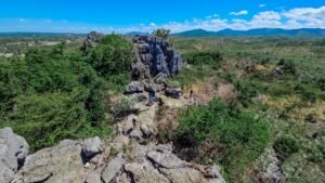 Rocky limestone trail leading up to Mt. Secret through open cogon grass terrain under direct sunlight