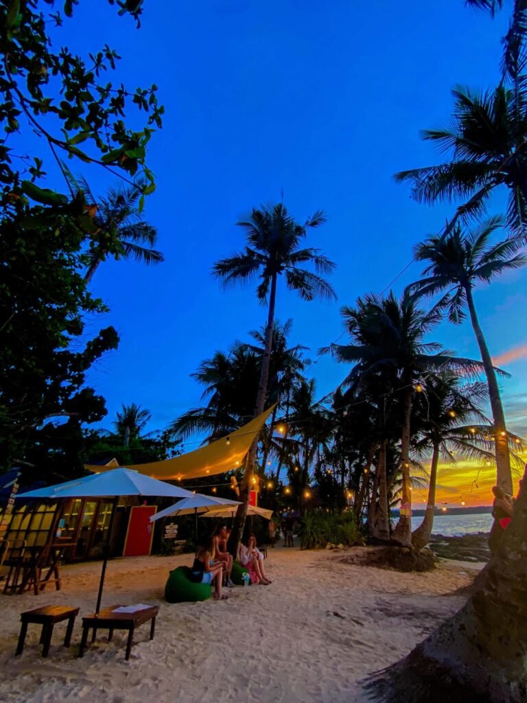 Coarse golden sand shoreline at Cloud 9 Siargao with palm trees lining the beachfront and calm water near the channel