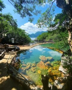 Visitors soaking in the large main geothermal pool at Maquinit Hot Springs with views of Coron Bay