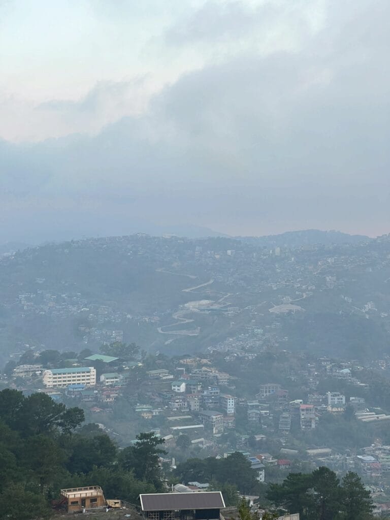 Wide rolling grassland and rock formations at the top of Mt. Yangbew with Benguet mountain ranges in the distance
