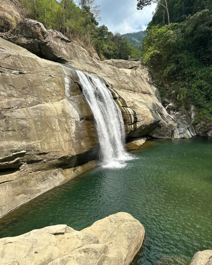 Swimmers and cliff divers in the wide natural pool at the base of Tangadan Falls, San Gabriel La Union