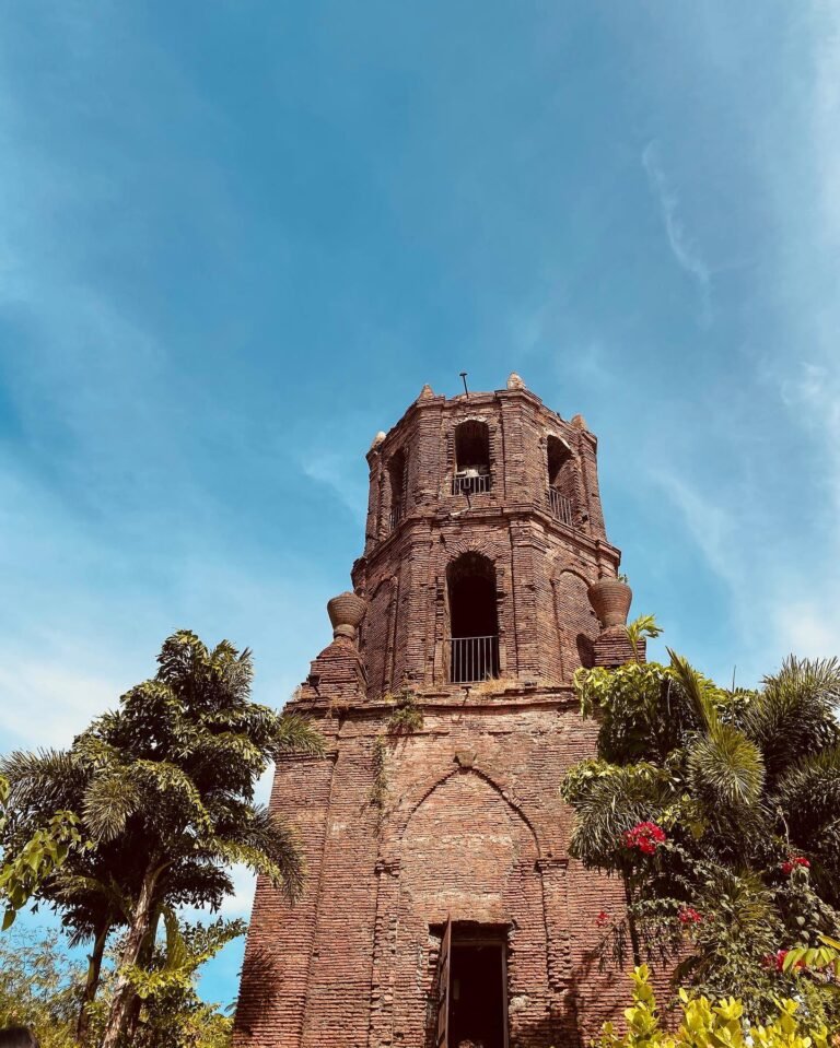 Bantay Bell Tower red brick facade rising from a green hill in Ilocos Sur Philippines against a blue sky