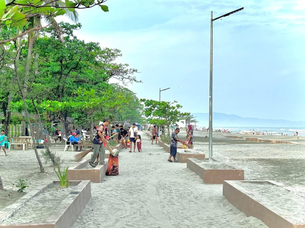 Fine white sand and gentle shore break at Tondaligan Beach in Bonuan, Dagupan with families wading near the waterline