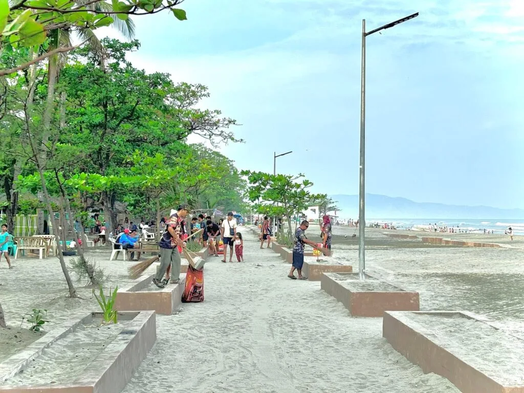 Fine white sand and gentle shore break at Tondaligan Beach in Bonuan, Dagupan with families wading near the waterline