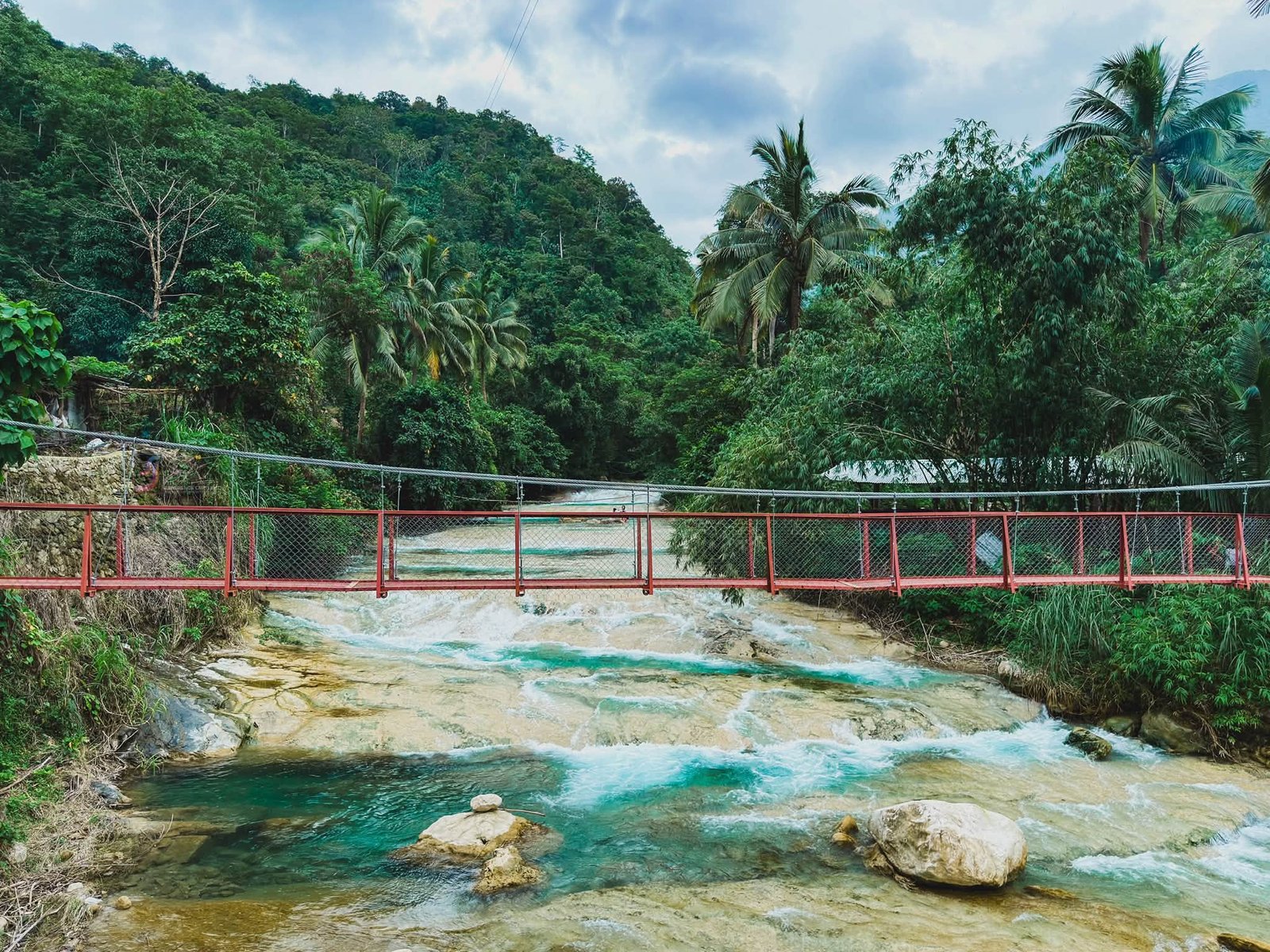 Lablabasan River flowing through Barangay Alfonso with clear blue water and forested canyon walls in Gregorio del Pilar, Ilocos Sur