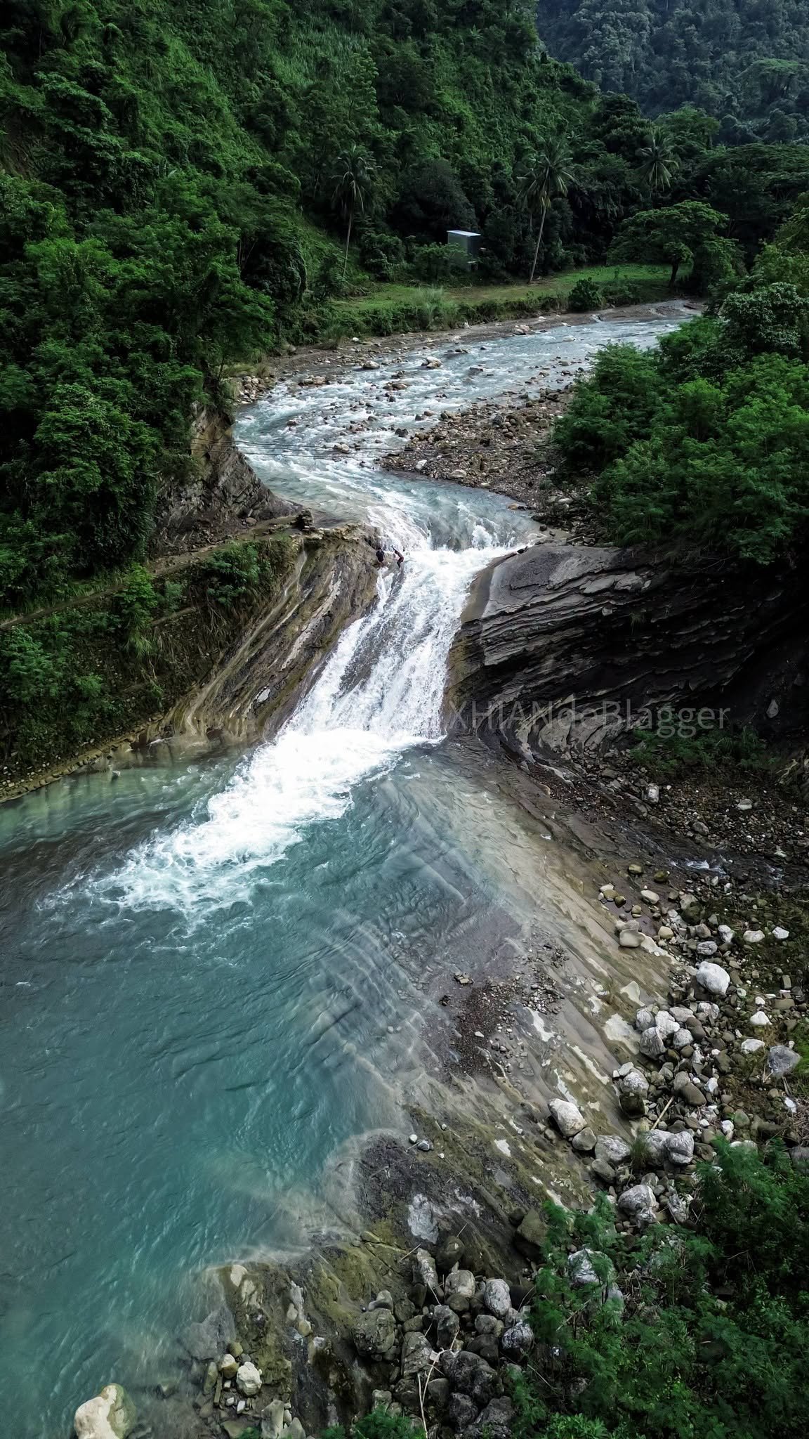 Natural plunge pool at the base of Kintukudan Falls with swimmers and sheer rock walls overhead