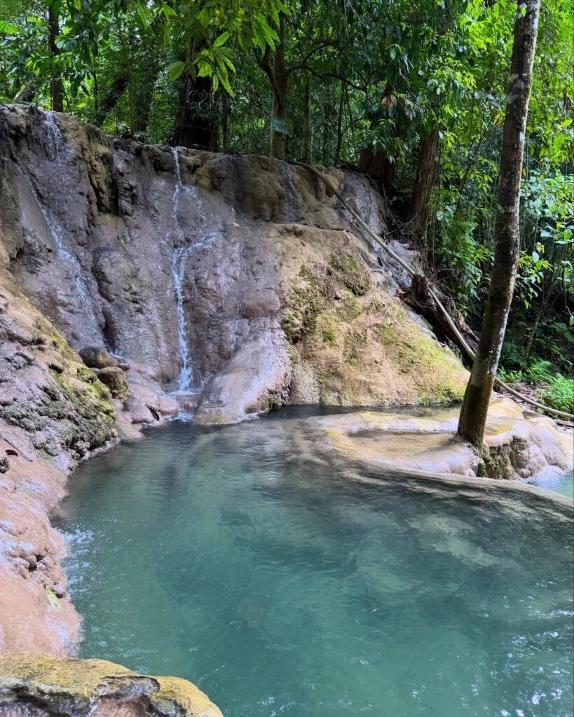 Aruyan Falls water terrace cascades flowing over stepped limestone rock into a wide jungle pool in Sablayan