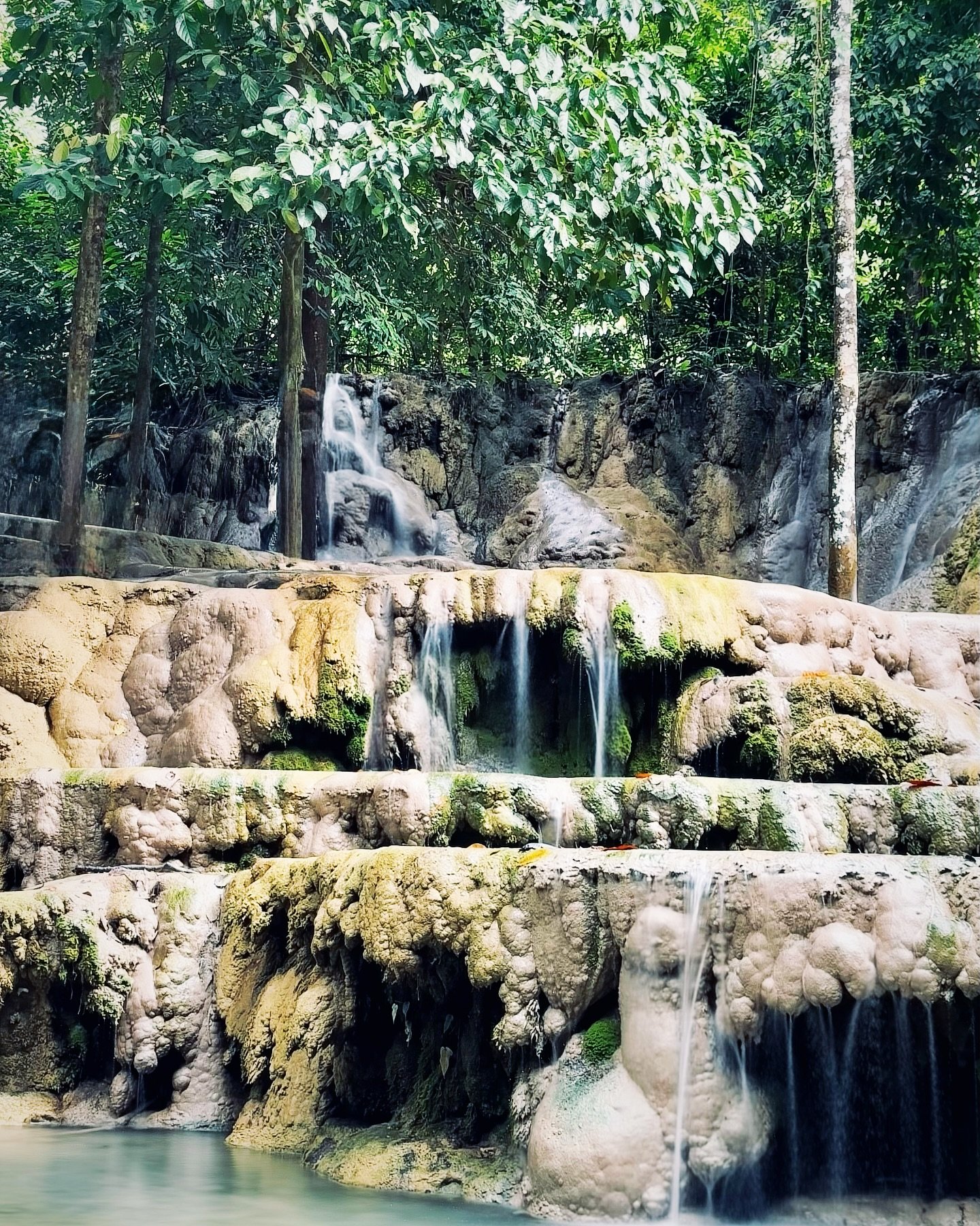 Aruyan Falls water terrace cascades flowing over stepped limestone rock into a wide jungle pool in Sablayan