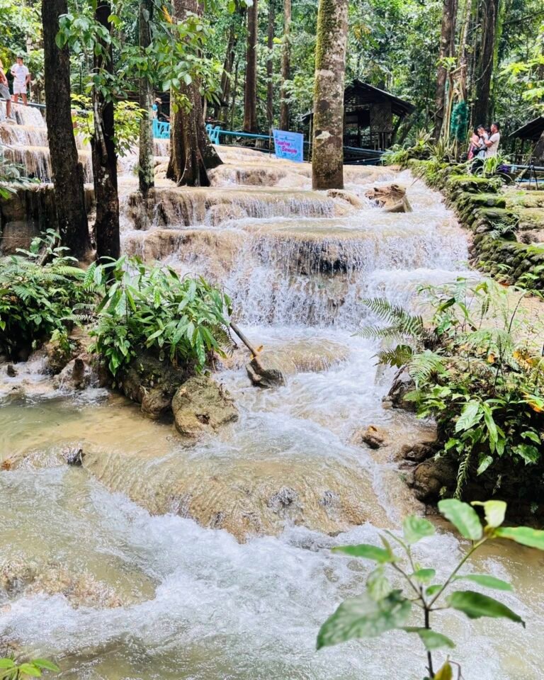Aruyan Falls water terrace cascades flowing over stepped limestone rock into a wide jungle pool in Sablayan