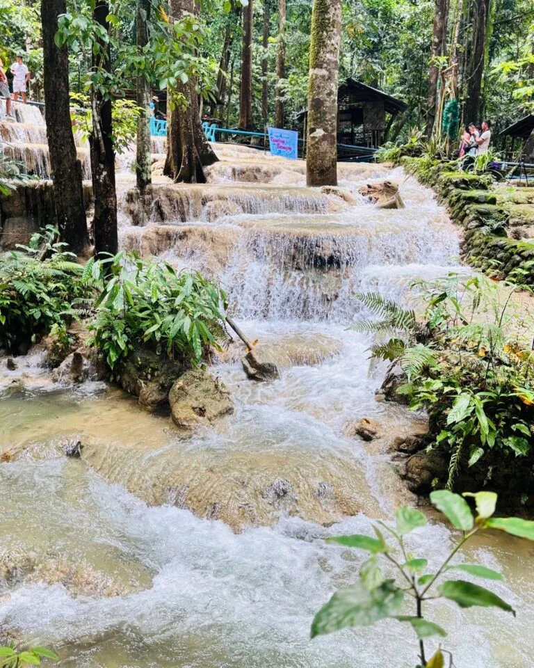 Aruyan Falls water terrace cascades flowing over stepped limestone rock into a wide jungle pool in Sablayan