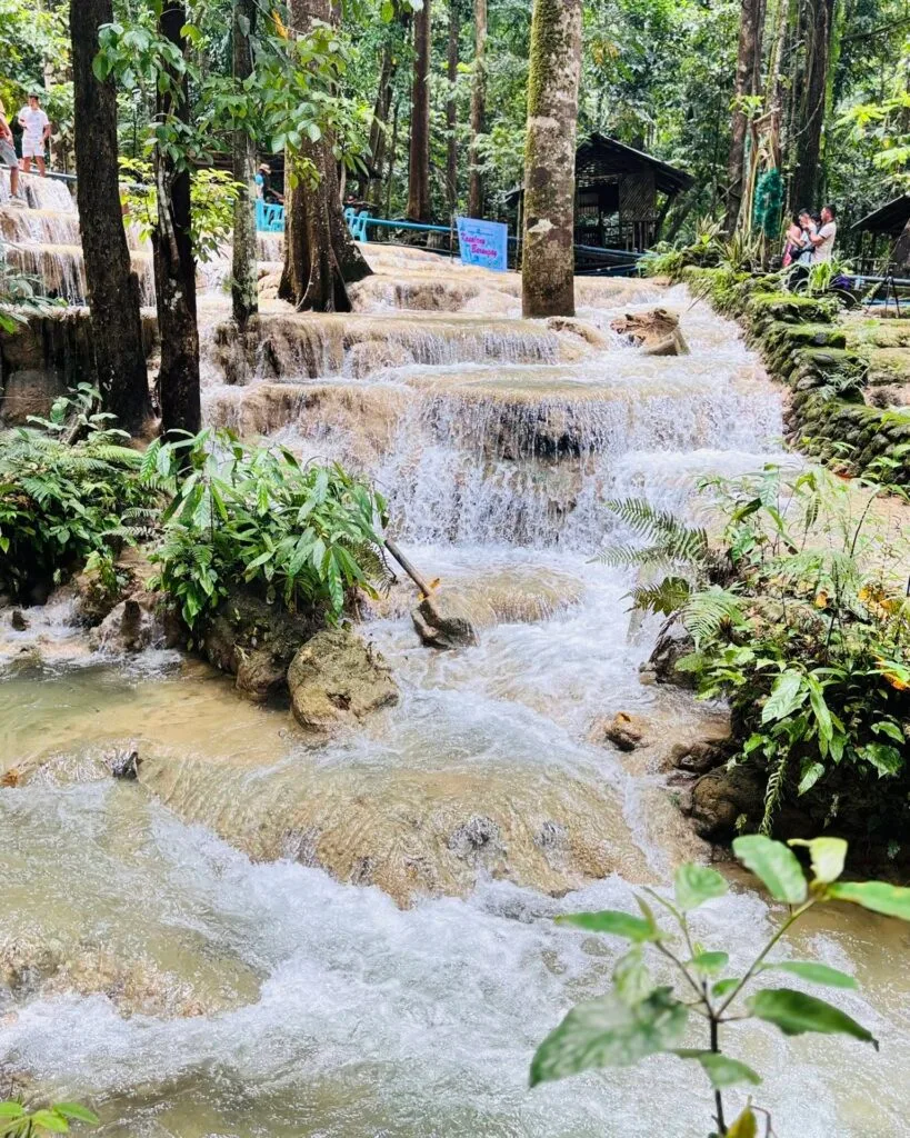 Aruyan Falls water terrace cascades flowing over stepped limestone rock into a wide jungle pool in Sablayan